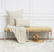 woven tan decorative pillow and bed throw on a bench