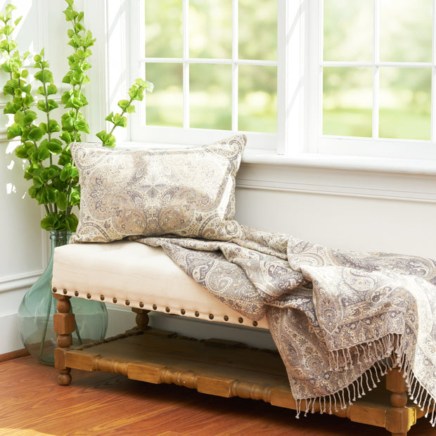 tan lumbar pillow with decorative paisley design on a bench
