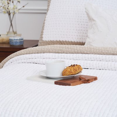 tan and white bed with a coffee cup sitting on top
